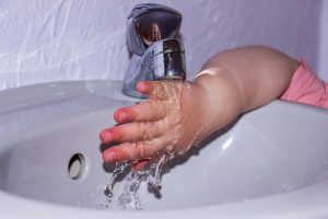 Main d'enfant et eau du robinet